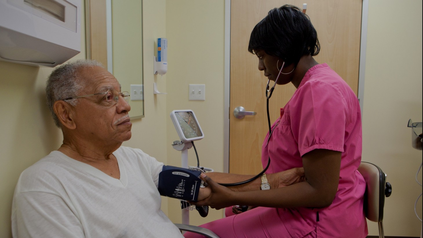 Nurse checking a elderly man's blood pressure