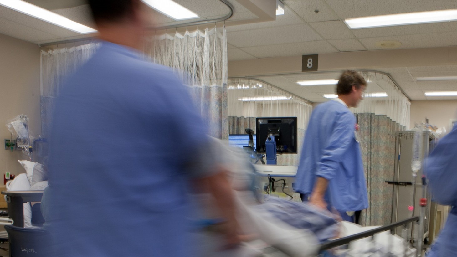 health care workers wheeling a patient on a gurney into surgery