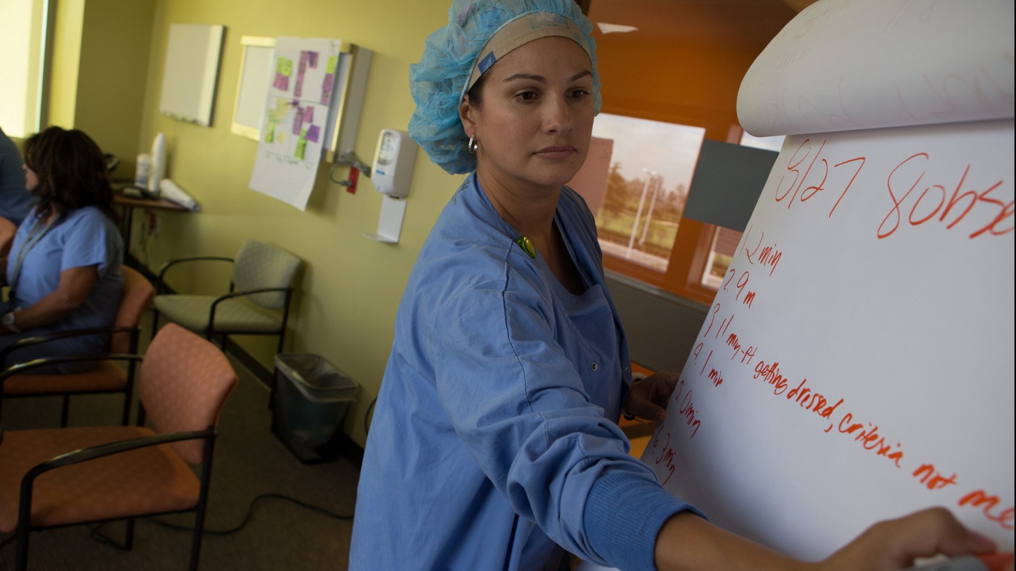 Health care worker in blue hairnet writing on a flip chart