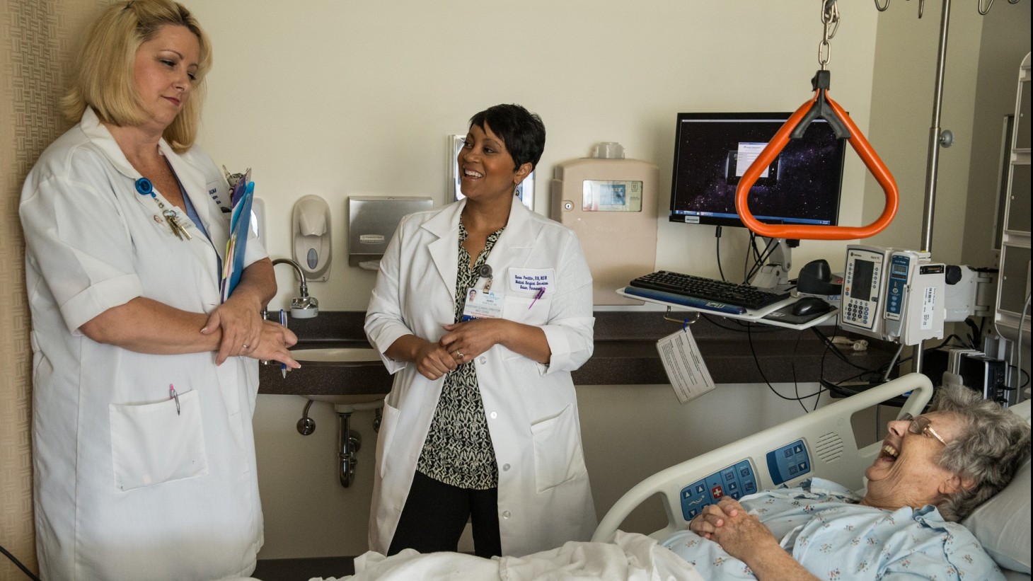 Two health care professionals in a hospital room with a patient