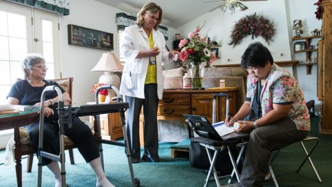 Two health care providers with a patient at her home