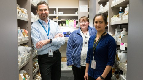 Three workers in a pharmacy supply room