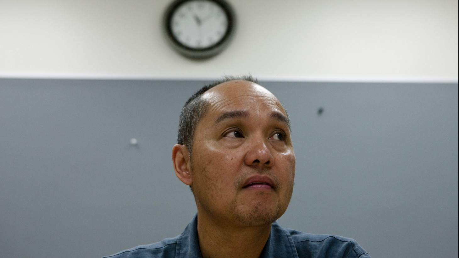 Anxious-looking man sitting under a clock